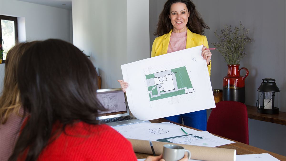 Arquiteta mostrando a planta de uma casa para uma cliente