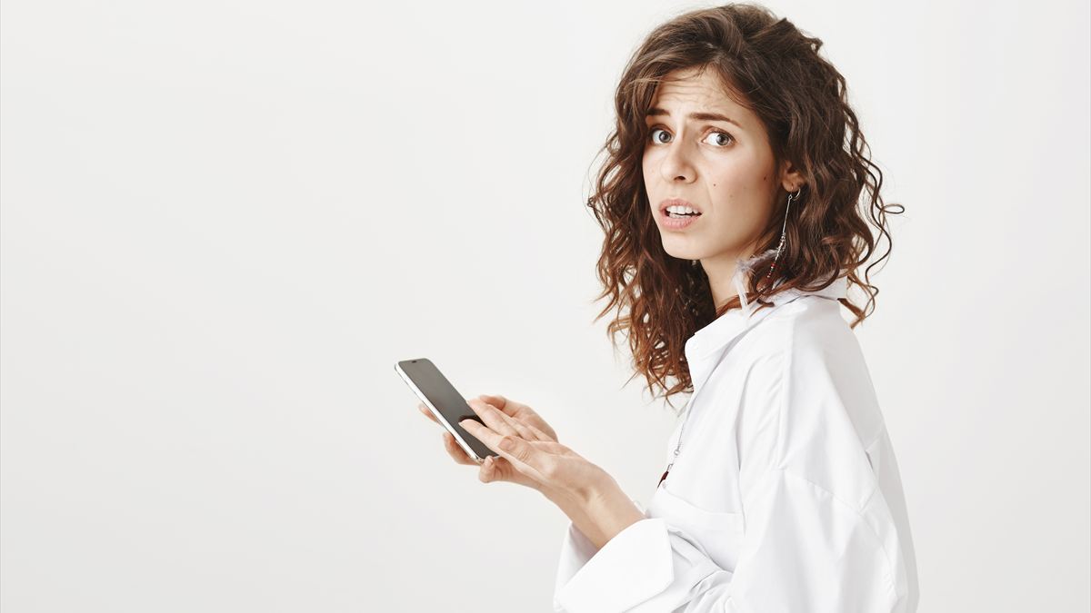 Mulher olhando desconfiada enquanto usa o celular