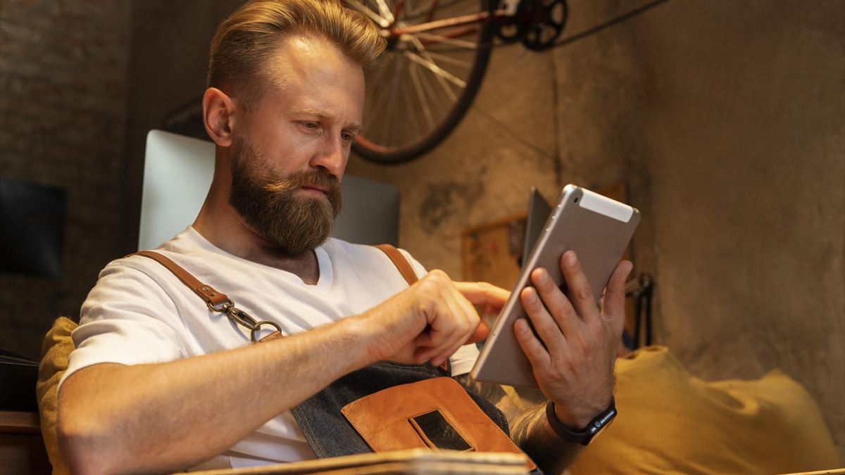 Profissional autônomo usando o tablet em sua oficina de bicicletas