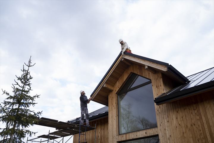 Casa em construção com profissionais trabalhando no telhado