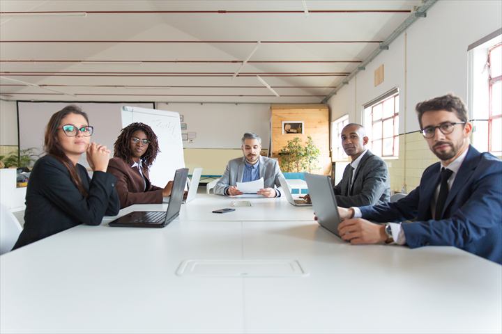 Equipe de executivos reunida à mesa da sala de reunião de uma empresa