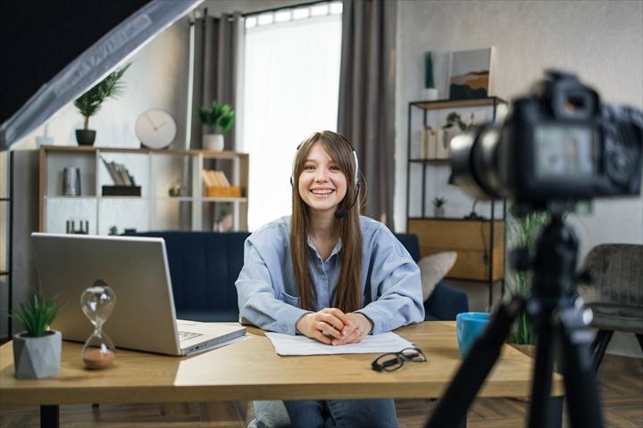 Mulher gravando uma aula online com câmera e notebook